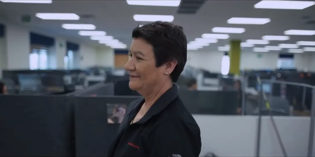 Smiling employee walking through an open-plan office during a corporate video shoot