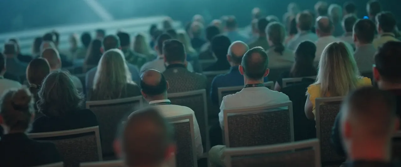 Público asistente a un evento institucional con escenario iluminado