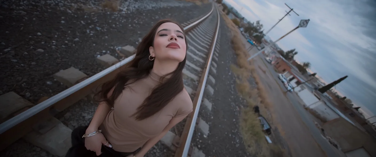 Young woman with long hair posing on railway tracks at dusk for a social media video shoot in Mexico